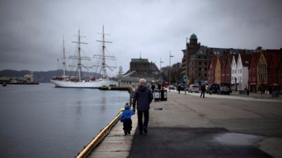 Một người đàn ông dắt một đứa trẻ dọc bến cảng thị trấn Bergen, Na Uy. Ảnh: Reuters