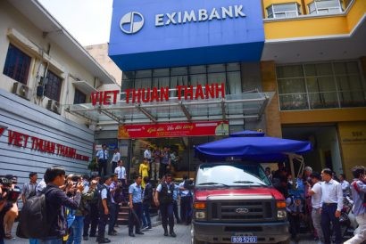Lực lượng công an khám xét và dẫn giải hai nhân viên Eximbank TP.HCM trưa 26-3 - Ảnh: HỮU THUẬN