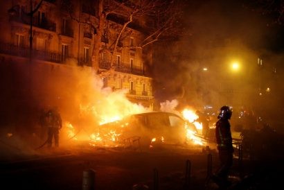  Lính cứu hỏa dập đám cháy do xe ô tô bị đốt ở Paris trong các cuộc biểu tình của phong trào Áo vàng. (Ảnh: Reuters)