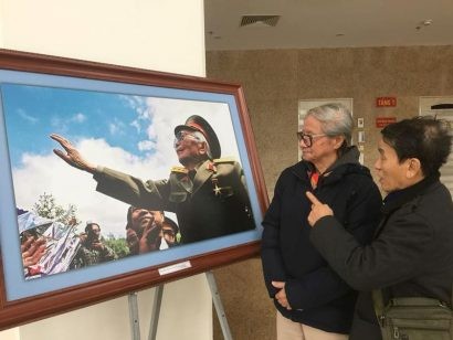  Nghệ sỹ Trần Định và khách thăm Triển lãm bên bức ảnh Đại tướng thăm lại Mường Phăng của ông