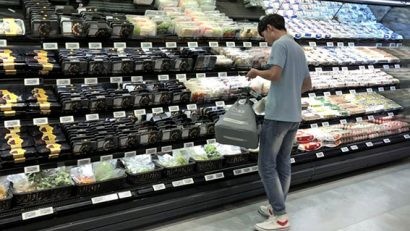 Nhân viên của siêu thị Hema đang lấy các hàng hóa do khách hàng đặt, cho vào giỏ hàng và chuyển đến khâu tiếp theo bằng hệ thống băng chuyền lắp đặt trên trần 