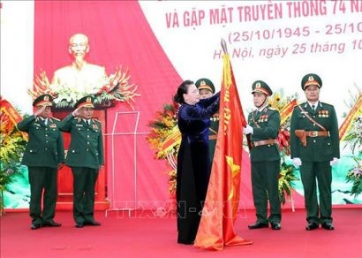 Chủ tịch Quốc hội Nguyễn Thị Kim Ngân gắn Huy hiệu Anh hùng LLVT lên lá cờ truyền thống của Tổng cục II. Ảnh: Trọng Đức /TTXVN 